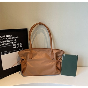 Détail de sac fourre-tout en nylon marron avec coutures en cuir et tablette de référence