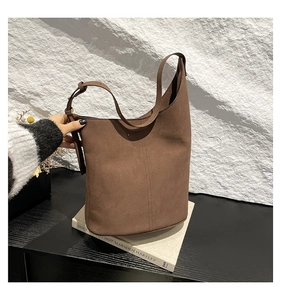 Close-up of deep brown suede bucket bag featuring vertical stitching and adjustable strap