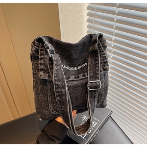 Dettaglio della borsa a tracolla in denim nero con fibbia argento e scritte bianche