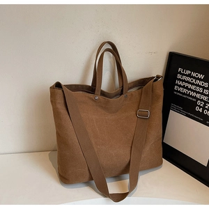 Detail of dark brown canvas tote bag with adjustable shoulder strap and metal buckle