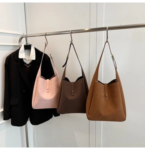 Three minimalist tote bags in pink, brown, and tan hanging on a minimalist display