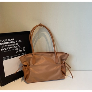 Détail d'un grand sac de voyage en nylon marron avec poignées en cuir et cordons latéraux