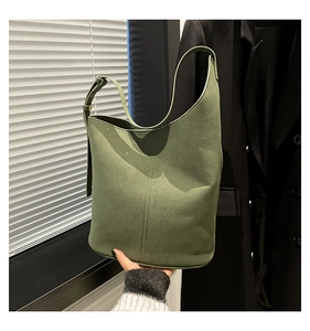 Detail of olive green suede bucket bag featuring adjustable strap and vertical stitching