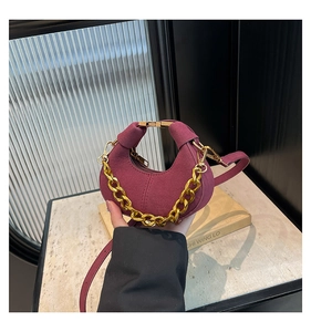 Detalle del mini bolso medialuna de ante granate con cadena dorada y bandolera