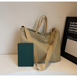 Large khaki canvas tote bag with shoulder strap shown next to a tablet for size reference