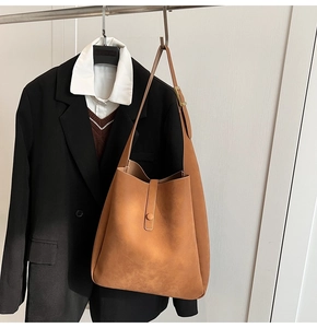 Detail of a large brown faux suede shoulder bag with adjustable strap and matte finish