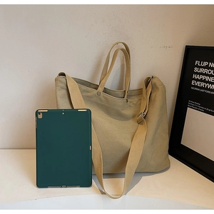 Close-up of large khaki canvas tote bag with adjustable strap and metal buckle detail