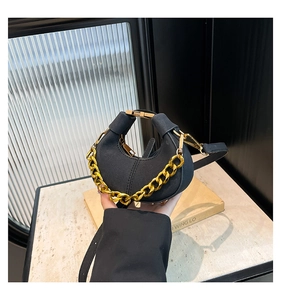 Detalle de bolso medialuna de cuero negro con cadena dorada y correa ajustable en soporte