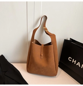 Detail view of caramel suede bucket bag featuring adjustable gold buckle and sleek strap