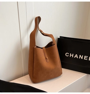 Detail view of a caramel leather tote bag with wide strap and minimalist metal buckle