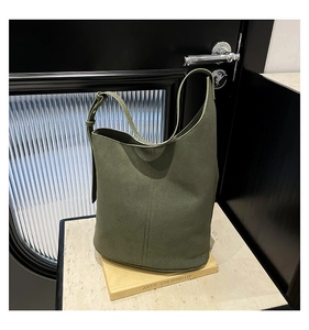 Close-up of army green suede bucket bag with adjustable strap on a minimalist stone setting