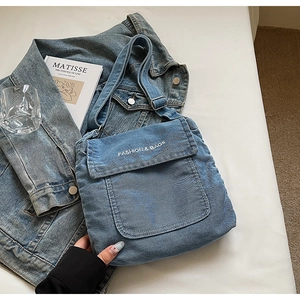 Dettaglio della borsa a tracolla in denim azzurro con testo ricamato fashion & bags