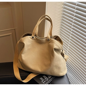 Close-up of beige canvas tote bag with wide straps and textured fabric on leather surface