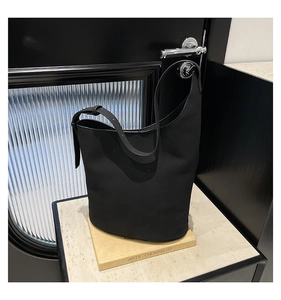 Minimalist black matte leather bucket bag shown on marble top for daily commuting
