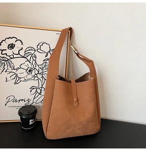 Detail of a brown Hobo shoulder bag with golden buckle and soft suede texture