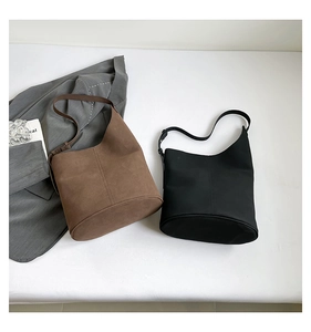 Flat lay of minimalist brown suede and black leather bucket bags for daily commute
