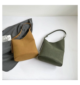 Overhead view of suede bucket bags in ginger and olive green with adjustable straps