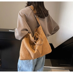 Close-up of a large brown suede tote bag featuring a wide comfortable shoulder strap