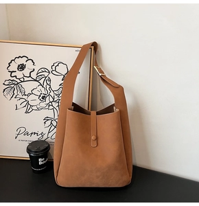 Close-up of caramel suede tote bag with wide shoulder strap and snap closure detail