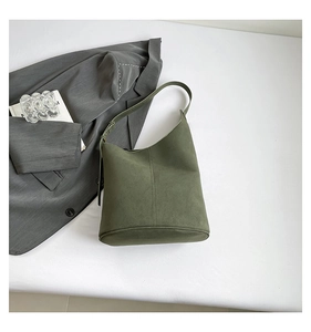 Detail of dark green matte leather bucket bag with adjustable strap and seamless stitching