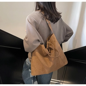 Detail of adjustable shoulder strap on brown canvas tote bag shown on model