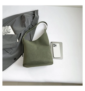 Detail of olive green suede tote bag with adjustable strap and vertical stitching accents