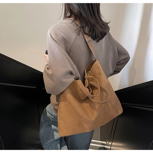 Close-up of brown suede canvas tote bag with adjustable metal buckle and leather texture