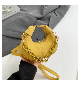 Detalle de bolso medialuna amarillo con cadena dorada y correa de cuero ajustable