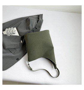 Army green leather shoulder bag with adjustable buckle strap on minimalist office desk