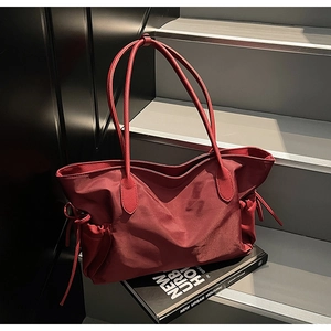 Vue détaillée du sac fourre-tout en nylon bordeaux avec des poignées en cuir renforcées