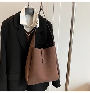 Close-up of brown suede hobo tote bag texture with elegant buckle and snap closure