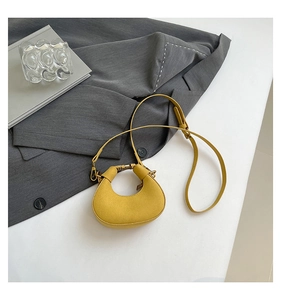 Detalle del mini bolso bandolera amarillo de media luna sobre chaqueta gris