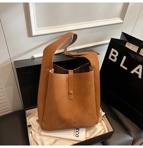 Detail view of a tan bucket bag with matte texture in a premium gift box set