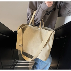 Detail of canvas tote bag showing thick texture, metal snap closure and adjustable strap