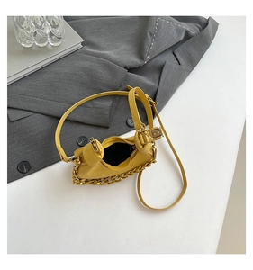 Detalle de bolso medialuna jengibre con cadena dorada sobre fondo blanco y ambiente de moda