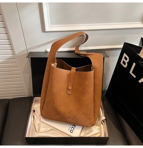 Close-up of caramel brown leather shoulder bag with matte finish in a gift box