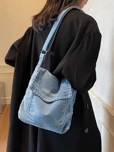 Borsa a tracolla in denim blu con tracolla regolabile e ricamo mostrata su un modello