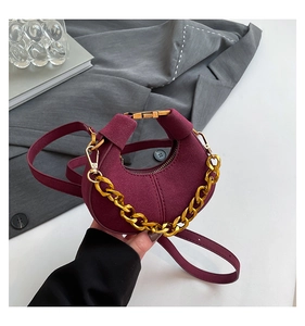 Detalle del bolso de media luna burdeos con cadena dorada y textura de ante