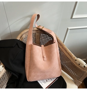 Pink frosted leather shoulder bag with gold buckle on a vintage chair