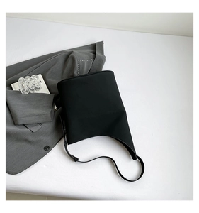 Detail of black matte fabric shoulder bag with adjustable strap and curved bucket design