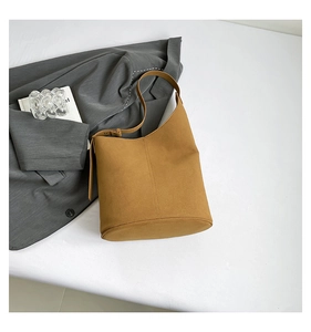Detail of adjustable strap and matte leather texture on tan bucket shoulder bag