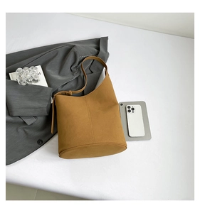 Detail of a brown leather bucket bag showing its circular base and adjustable strap