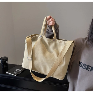 Detail of khaki heavy-duty canvas tote bag with adjustable shoulder strap and metal rivets