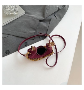 Vista detallada del mini bolso media luna burdeos con cadena dorada sobre una chaqueta