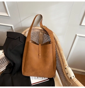 Detailed view of caramel suede shoulder bag with gold buckle on a vintage wooden chair