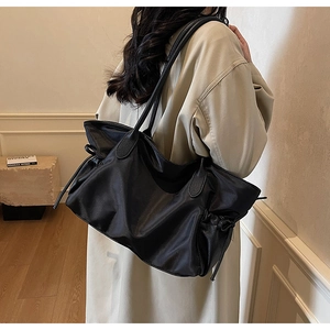 Détail d'un grand sac fourre-tout en nylon noir avec poches latérales à cordon et anses cuir