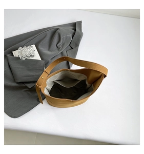 Detail view of large brown bucket bag with adjustable strap and internal zipper pocket