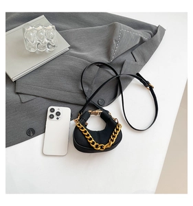 Detalle de bolso bandolera negro de media luna con cadena dorada y correa de piel fina