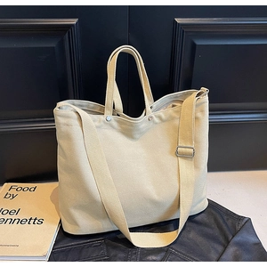 Detail of beige canvas tote bag with adjustable strap and metal rivet reinforcements
