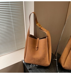 Detail view of caramel faux leather tote bag with buckle strap and gold hardware